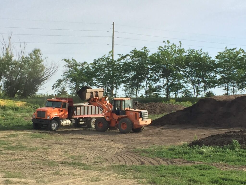 Tractor loading manure from feedlot in semi truck